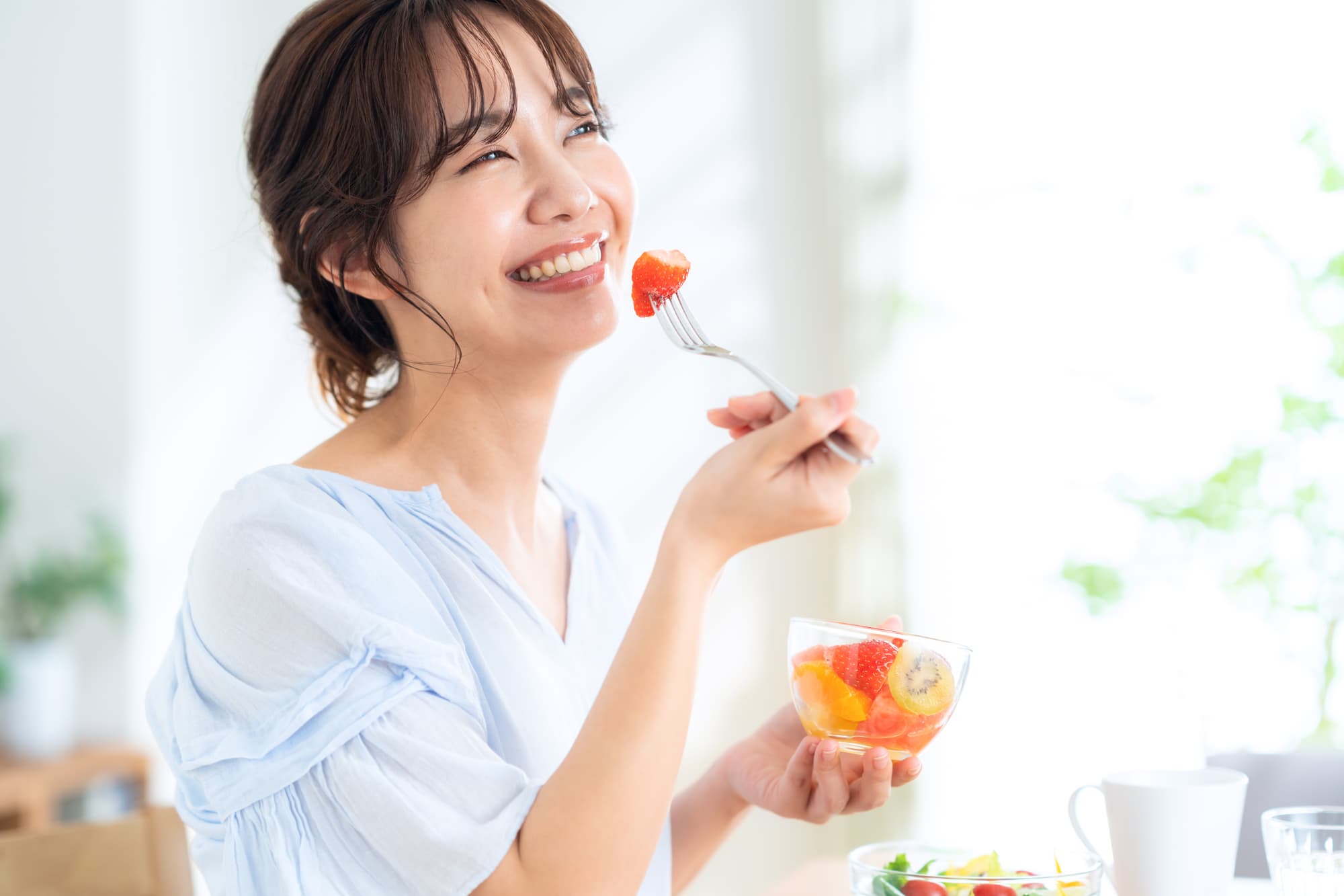 笑顔でおいしそうにフルーツを食べる女性