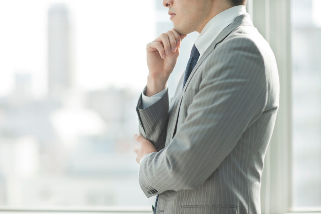 審美歯科治療の費用はどうして高いのかを考えている男性