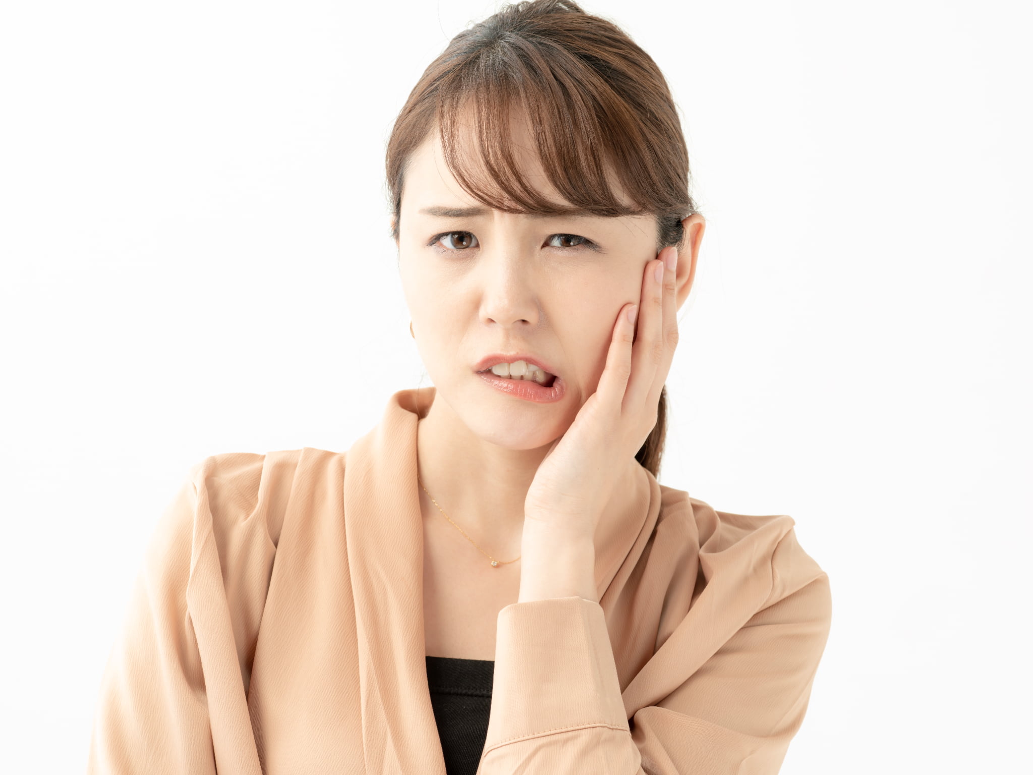 顎関節症で痛む顎を押さえる女性