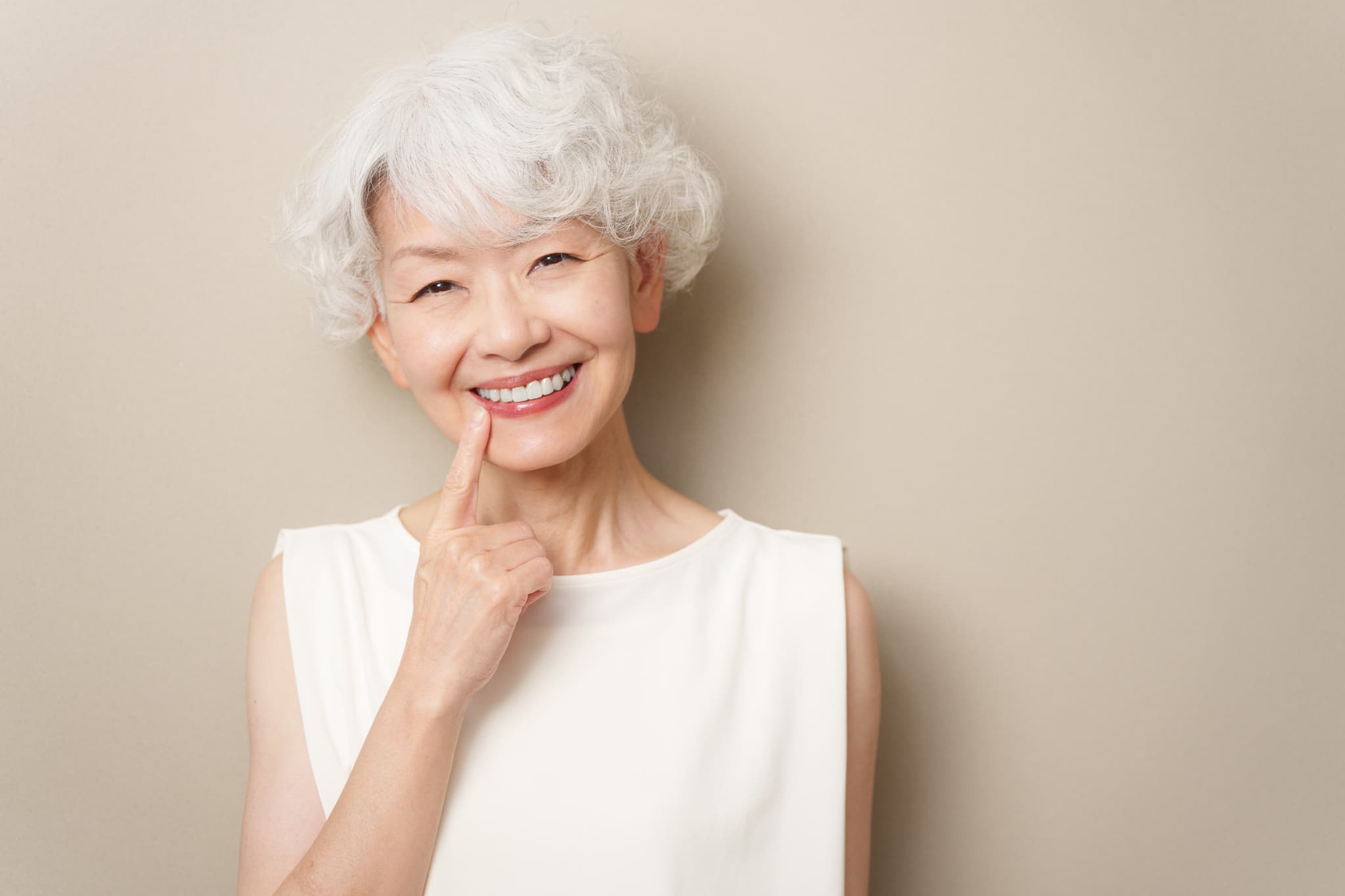 入れ歯を指さして笑顔を見せる高齢女性