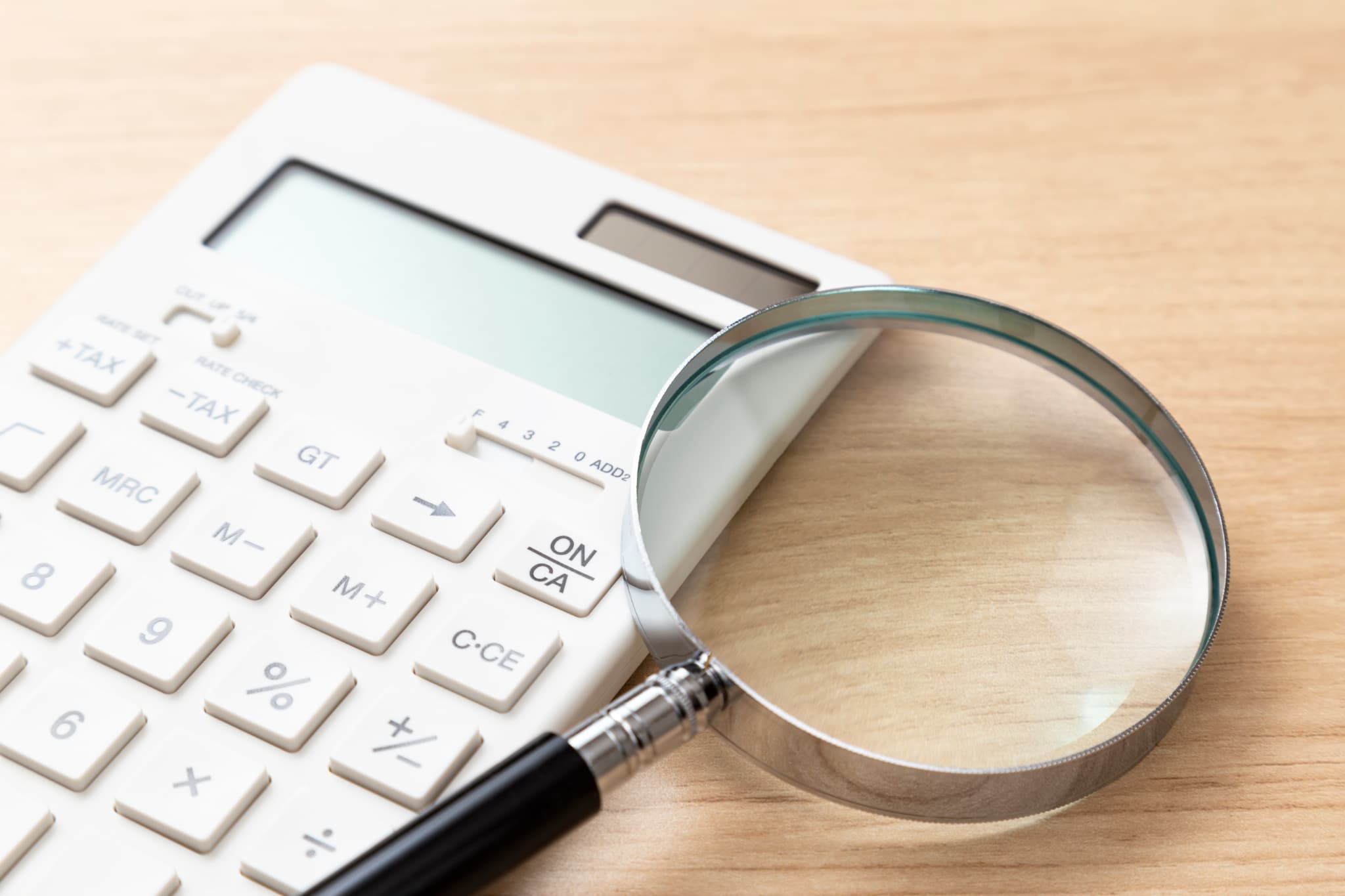 計算機とルーペで出っ歯の矯正にかかる費用を調べるイメージ