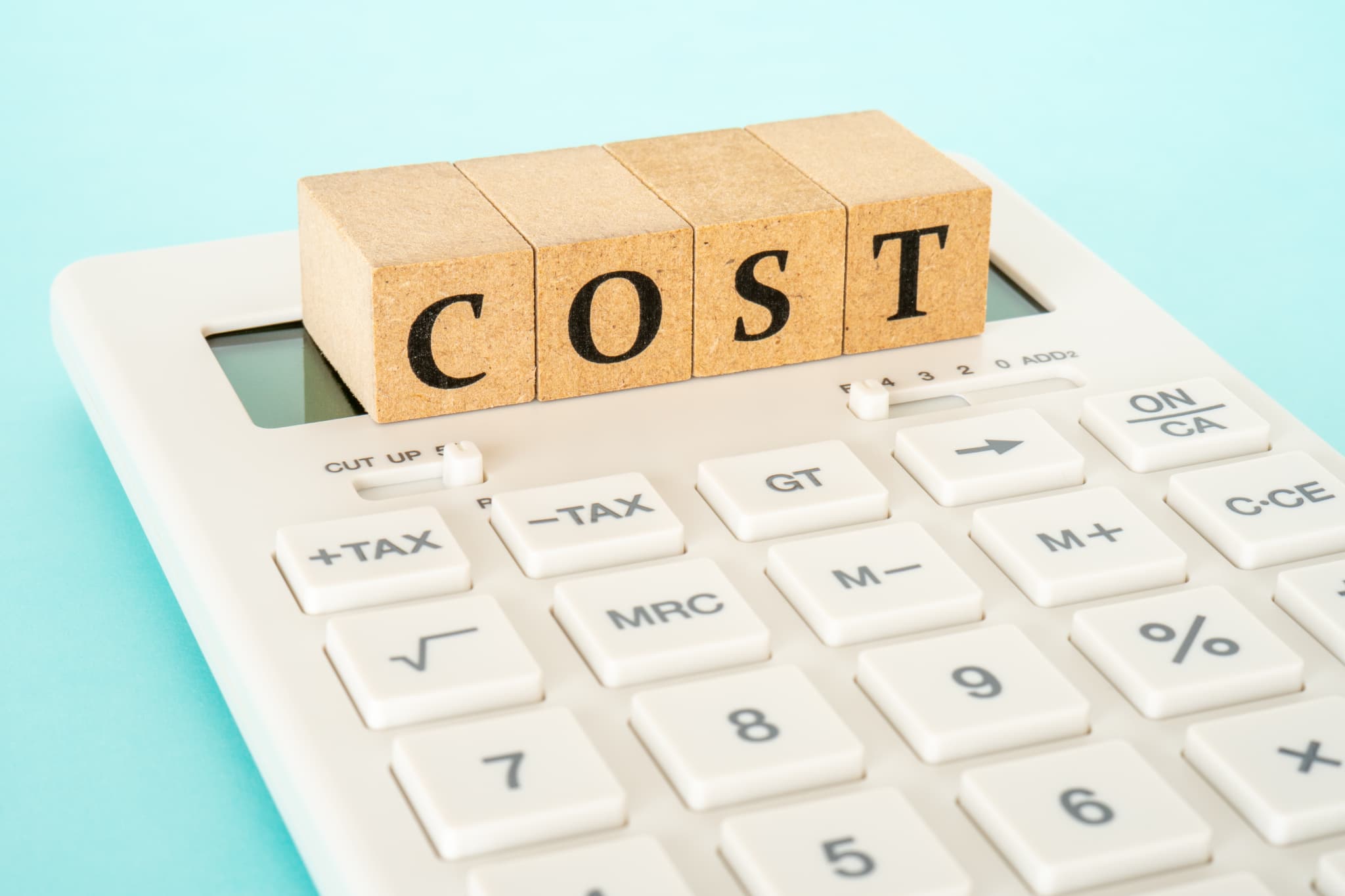 前歯をインプラントにする場合にかかる費用を示す計算機とCOSTの文字の書かれたブロック