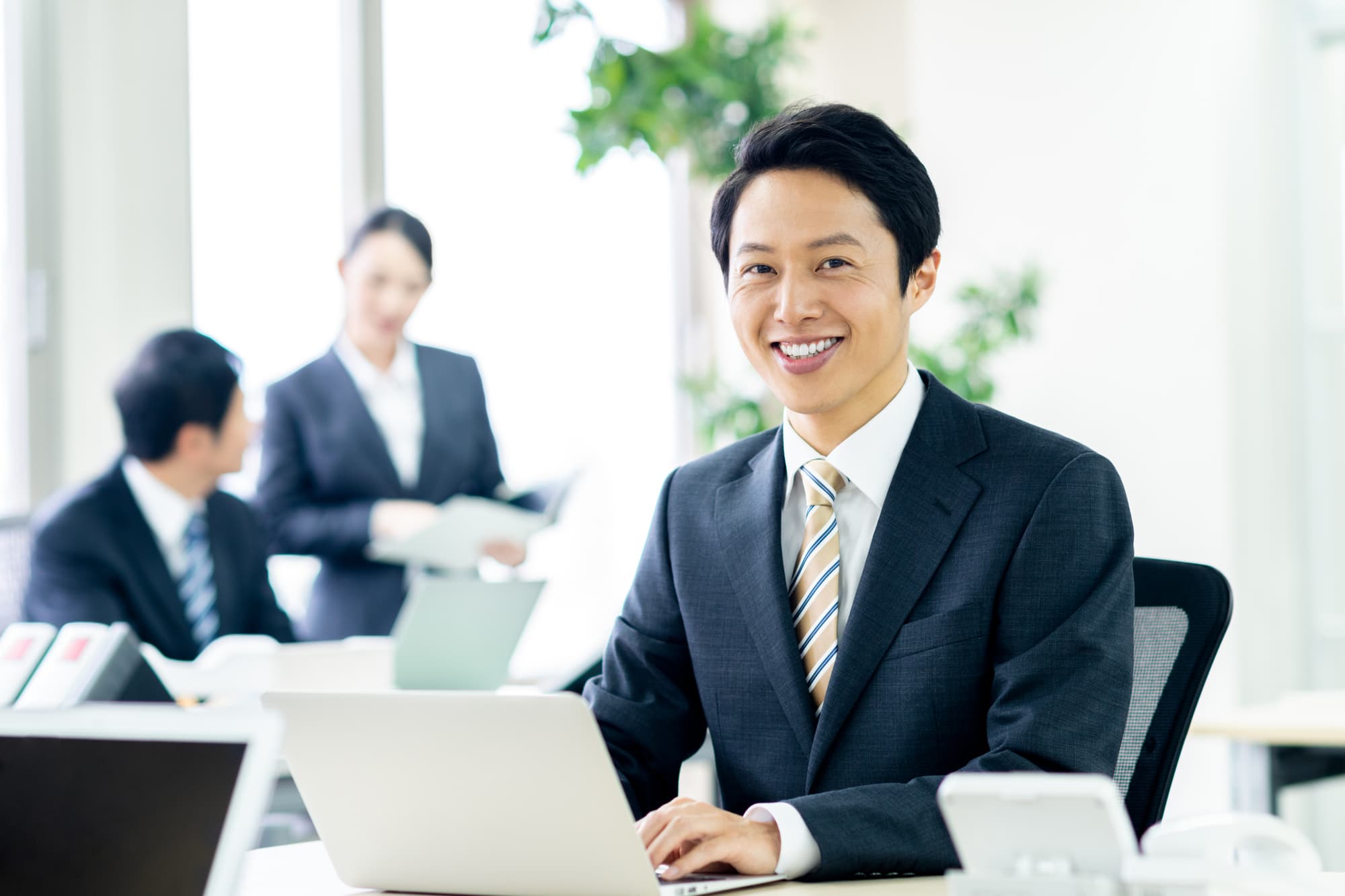 歯周外科治療を受けた男性が笑顔で仕事をしているイメージ